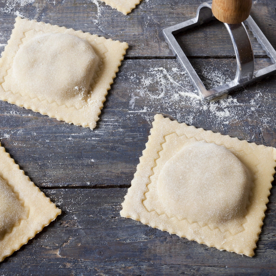 Hjemmelavet ravioli med pastaudstyr i aluminium og træhåndtag, klar til madlavning