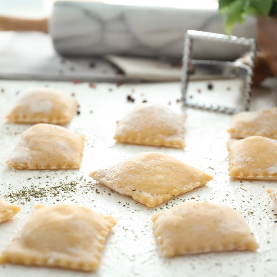 Fremstilling af ravioli med pastaudstyr i aluminium og træhåndtag, frisk pasta på træbord
