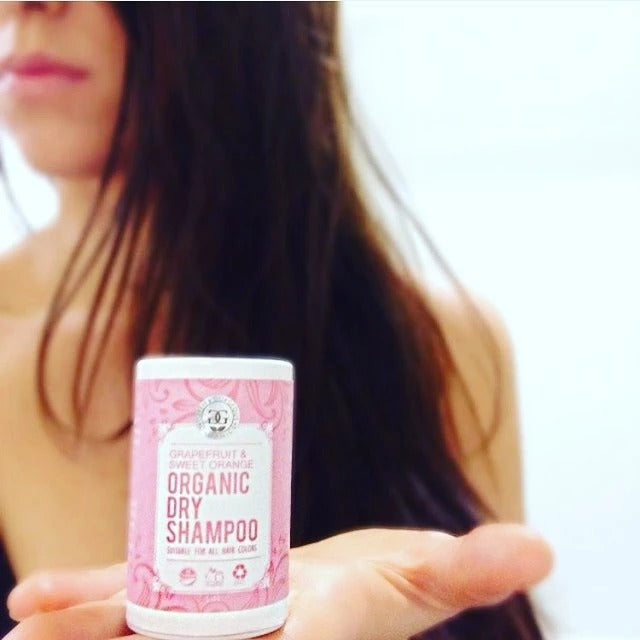 Person holder økologisk tørshampoo med grapefrugt & appelsin, naturlig hårpleje