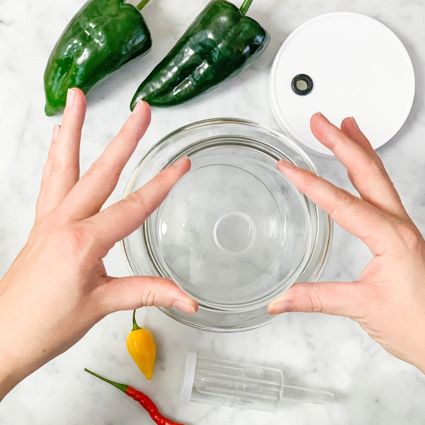 Hånd, der forbereder fermenteringsglas med friske grønne chili til hjemmelavet hot sauce