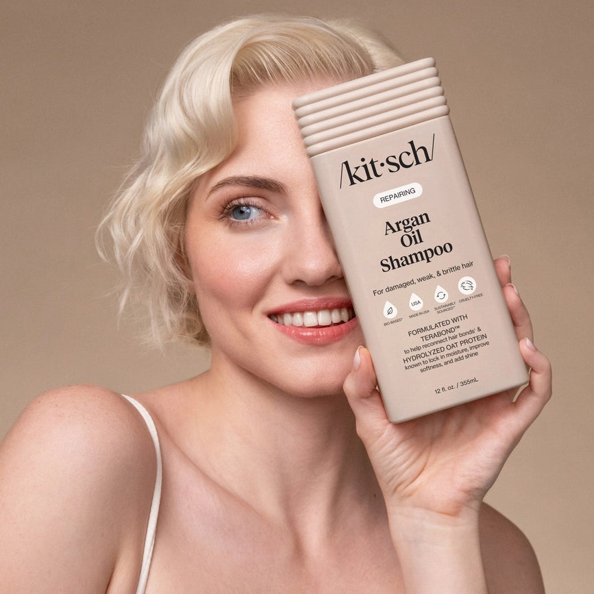 Kvinde med blond, bølget hår holder Kitsch argan olie shampoo, smilende