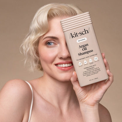 Kvinde med blond, bølget hår holder Kitsch argan olie shampoo, smilende