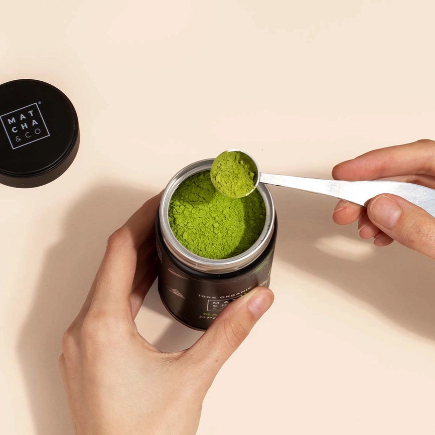 Åbnet matcha-krukke med grøn matcha pulver og måleske