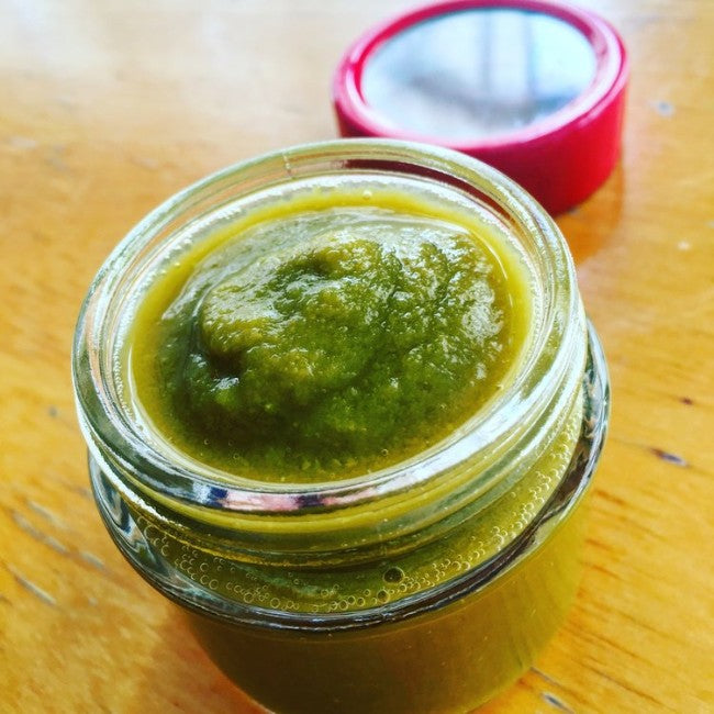 Gennemsigtig glasbeholder med grøn hot sauce på træbord, klar til brug i hjemmelavet hot sauce fermentering