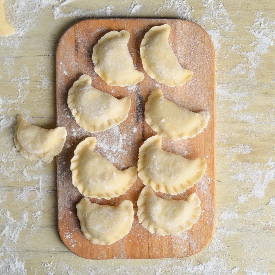 Færdige hjemmelavede ravioli og pierogi på træbord med blåbær og yoghurt