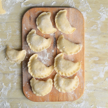 Færdige hjemmelavede ravioli og pierogi på træbord med blåbær og yoghurt