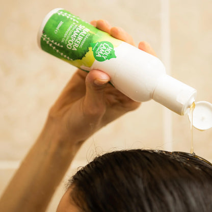 Person, der vasker hår med shampoo under bruser