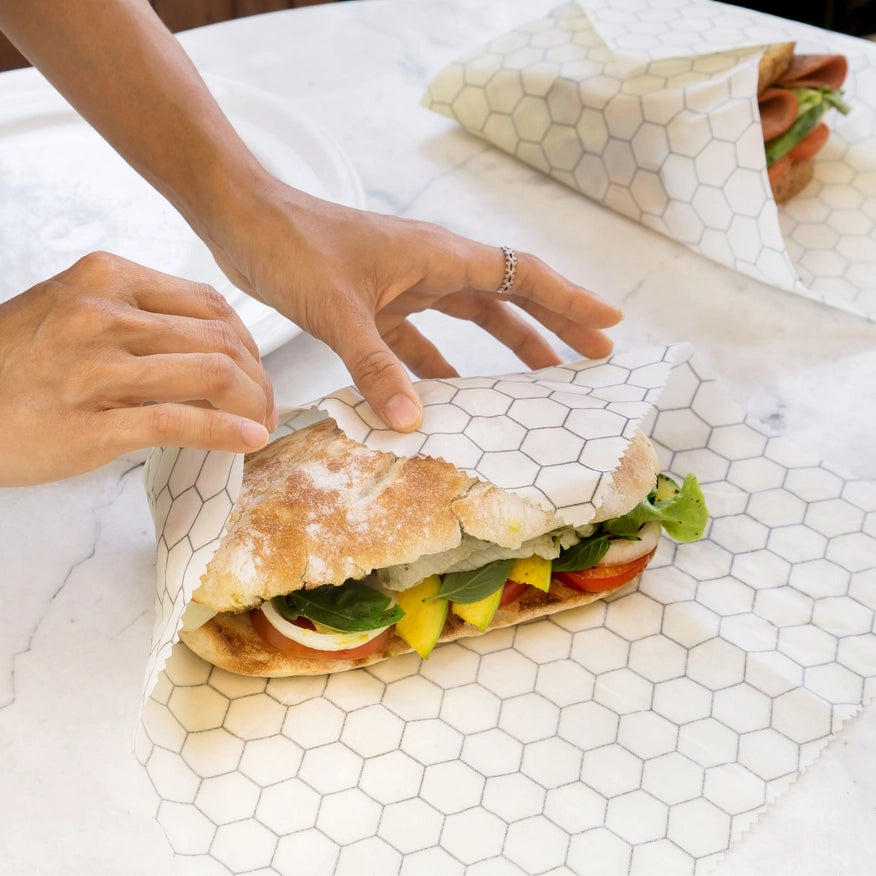Person pakker sandwich ind i økologisk bivokspapir, miljøvenlig madindpakning