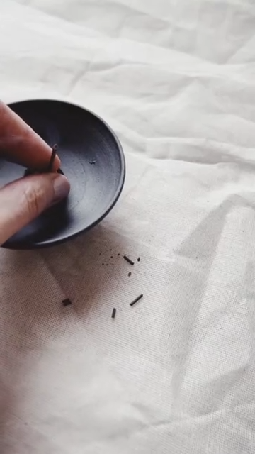 Hånd, der placerer røgelse i sort smudging skål
