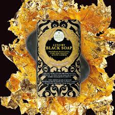 Luksus black soap fra Nesti Dante, i guld- og sort design, omgivet af guldglitter