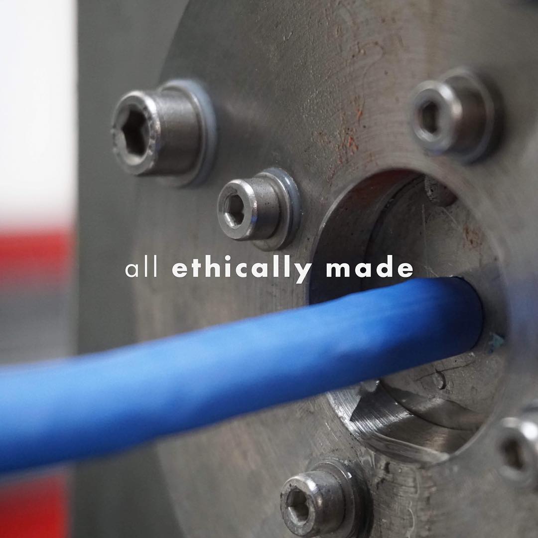 Et billede af en miljøvenlig produktionsproces med metaldele og en blå genbrugsledning, der understreger etisk produktion
